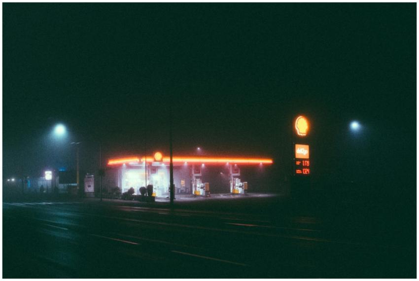 A foggy night scene of an illuminated gas station,