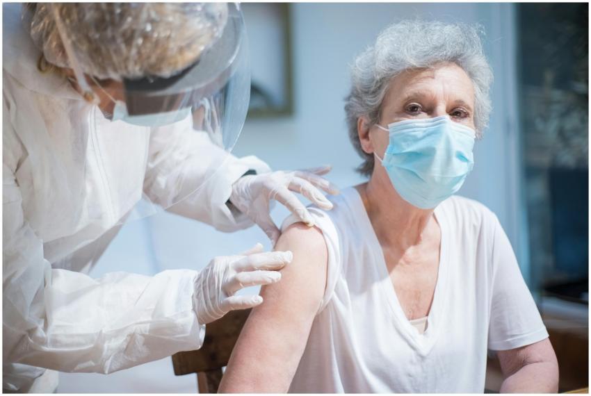 Senior woman wearing a mask getting vaccinated by