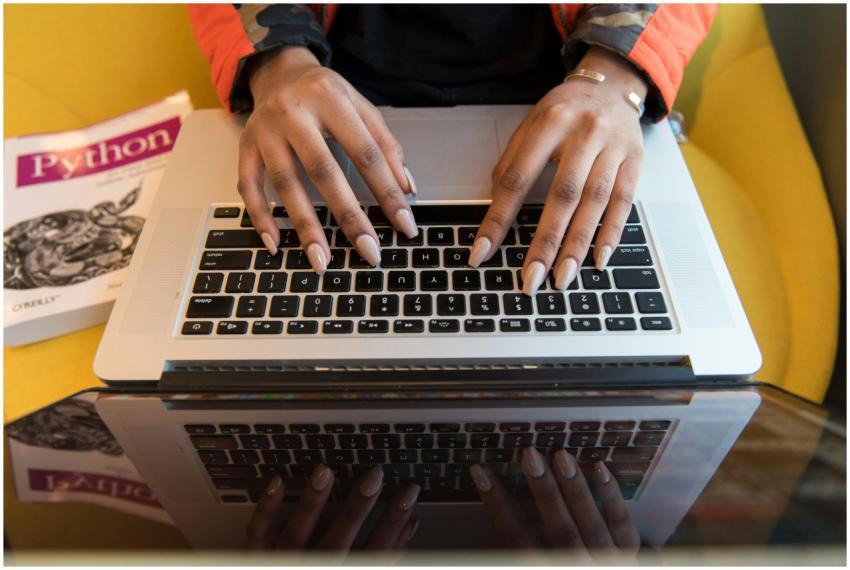 A person typing on a laptop with a Python programm