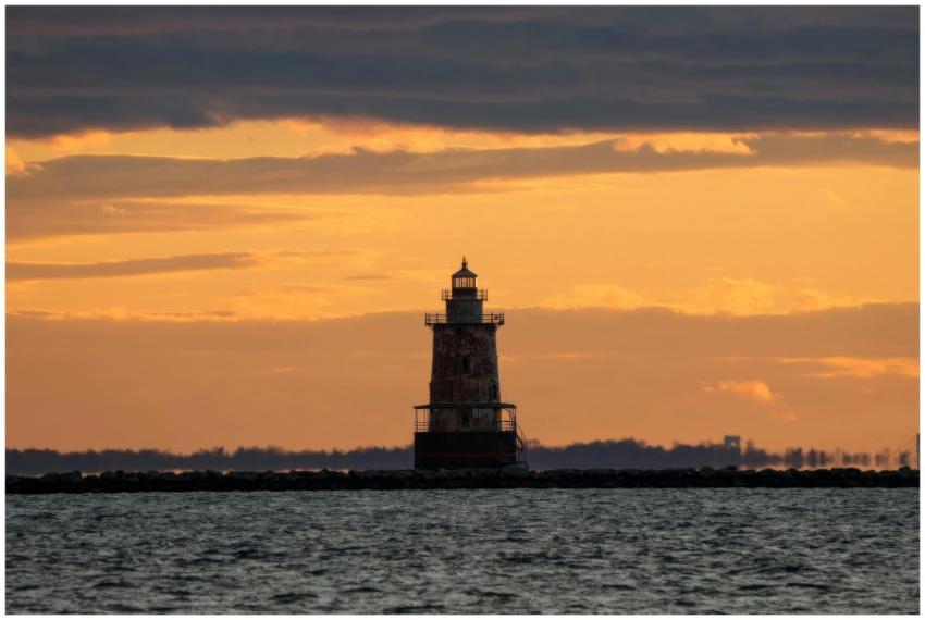 A picturesque lighthouse silhouette against a vibr