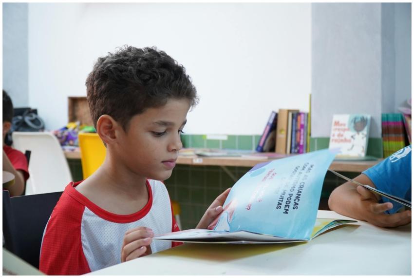 A young boy engrossed in reading a book in a class