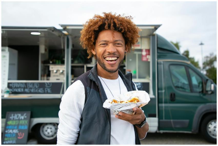 Smiling man holding street food near a food truck