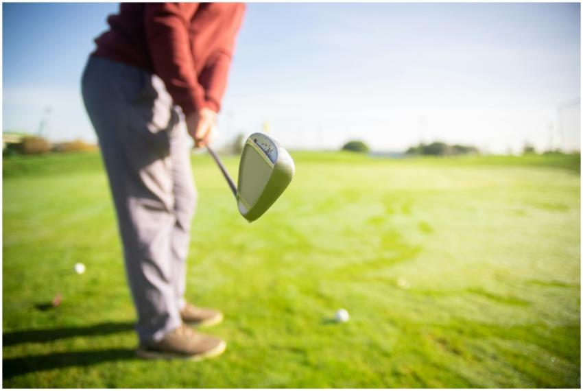A golfer readies for a swing on a sunny course, sh