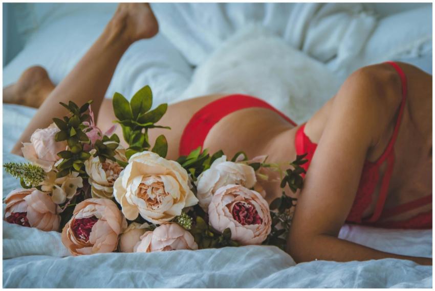 A woman in red lingerie is relaxing on a bed adorn