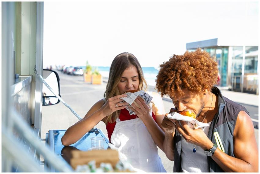 Hungry multiethnic couple eating with appetite ham