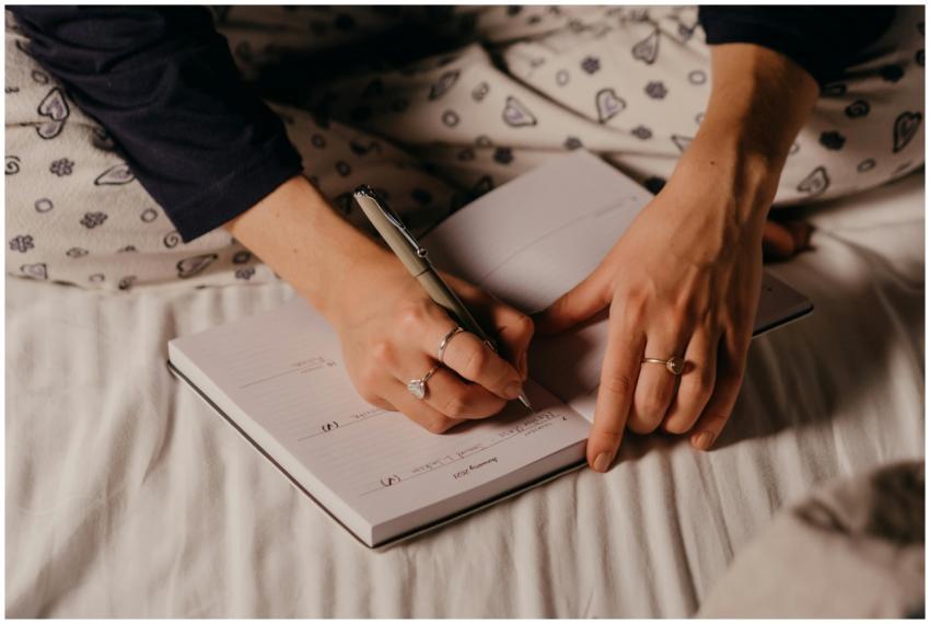 Close-up of a person's hands writing in a journal,