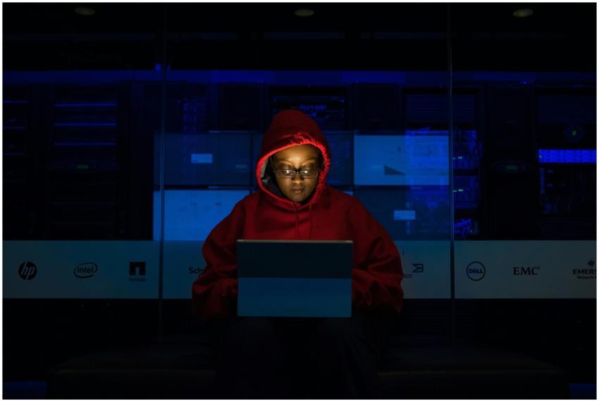 Focused woman in a red hoodie using a laptop in a