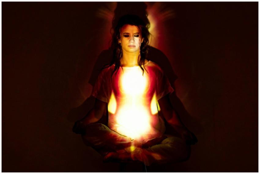 A woman in meditation surrounded by a radiant aura