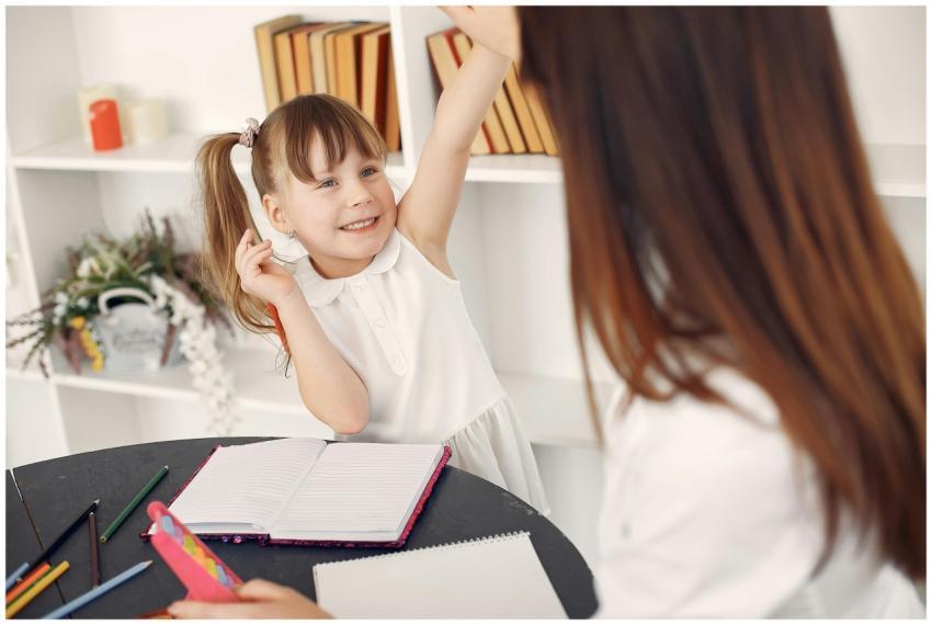 Cheerful child in a classroom raising hand during