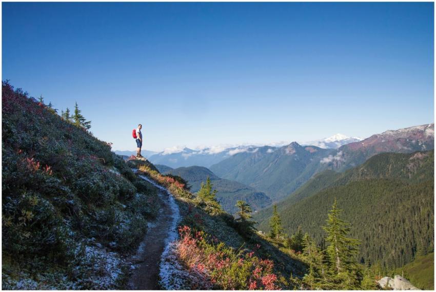 A hiker with a backpack stands on a trail overlook