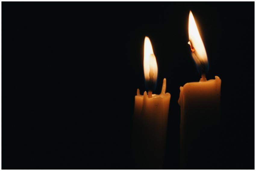 Close-up of two burning candles illuminating the d