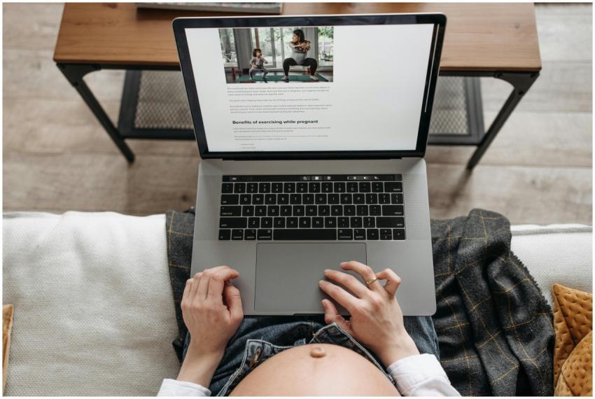 Pregnant woman uses laptop to read about exercisin