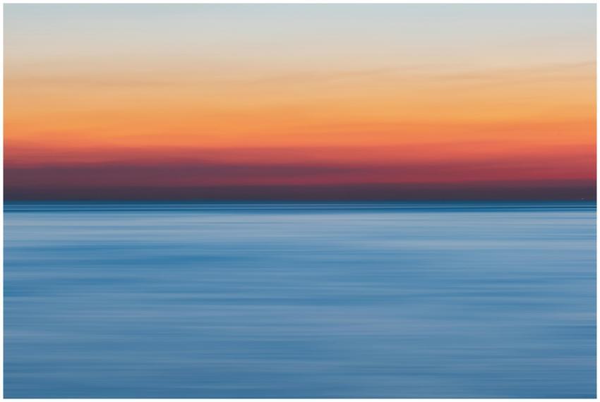 A colorful sunset over a calm ocean, perfect for v