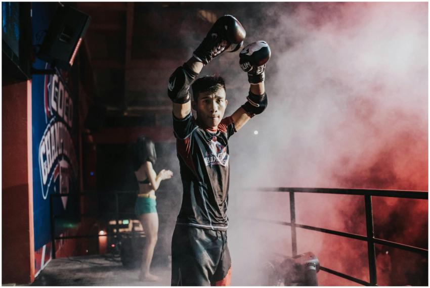 Boxer in dramatic lighting raises arms in victory