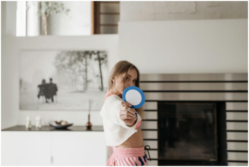 A woman poses indoors holding a round blue cutout