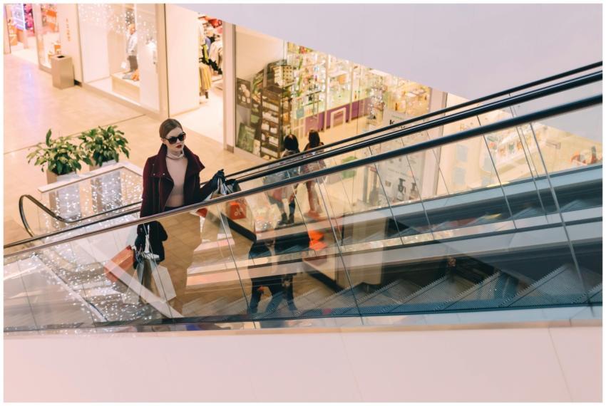 A fashionable woman ascends an escalator in a chic