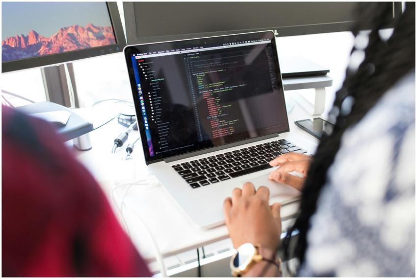 A woman coding on a laptop in a modern office envi
