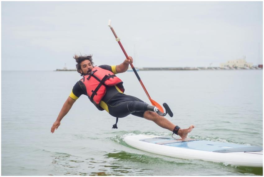 A man falls from a paddleboard into the ocean, wea