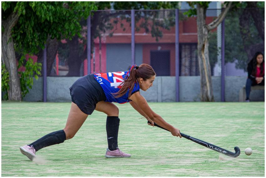 Dynamic photo of a female field hockey player stri