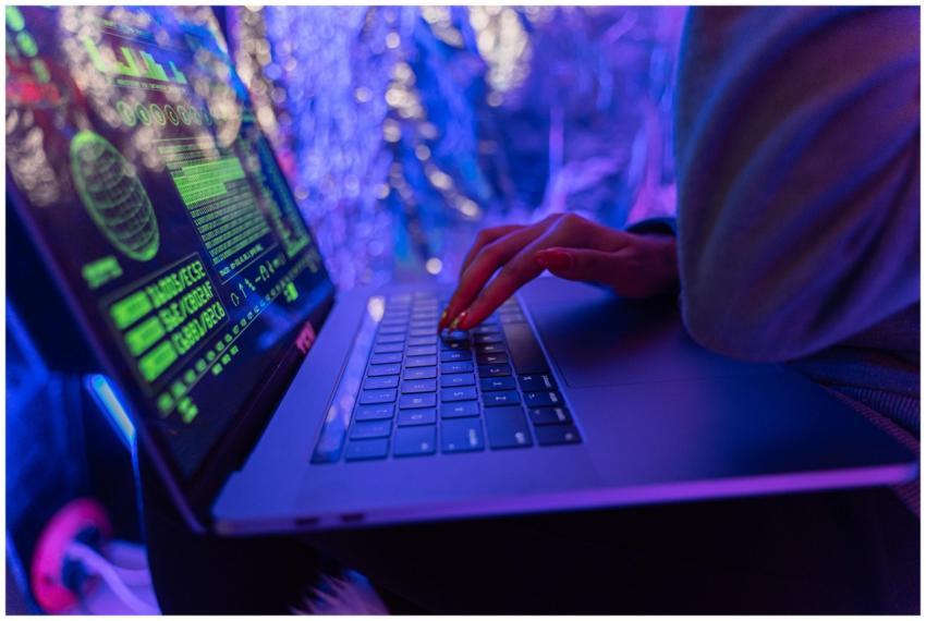 Close-up of hands typing on a laptop displaying cy