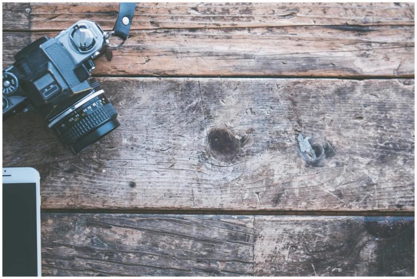 A vintage camera and smartphone placed on a rustic