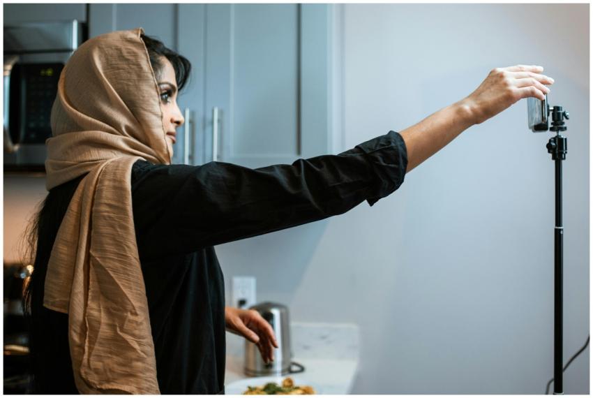 A Muslim woman in a hijab records a cooking video
