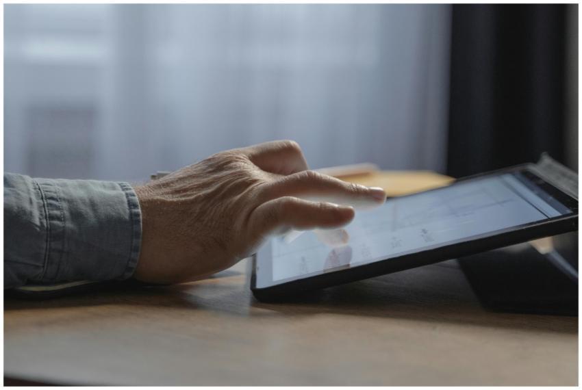 A person's hand interacting with a digital tablet