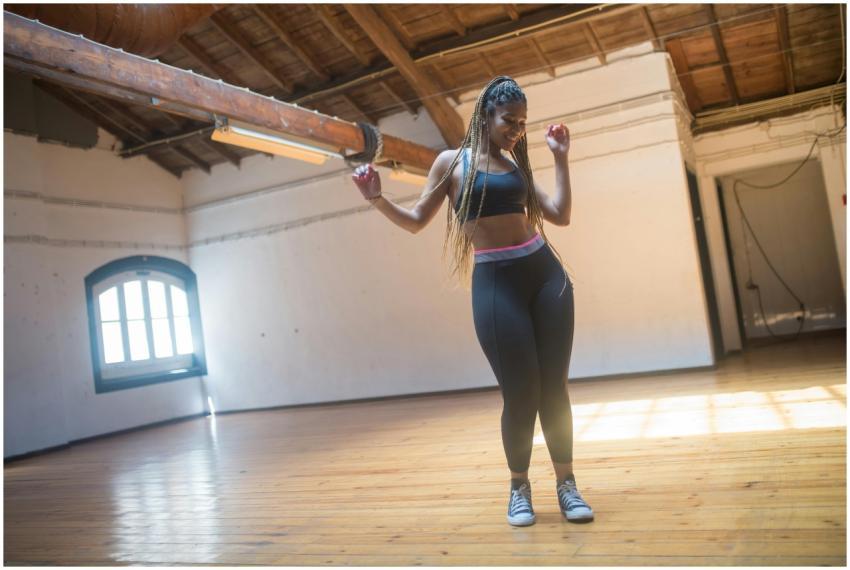 Joyful woman in activewear dancing in a sunlit stu