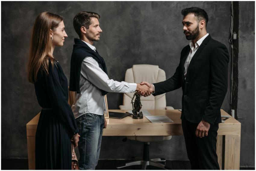 Three business professionals engage in a formal ha