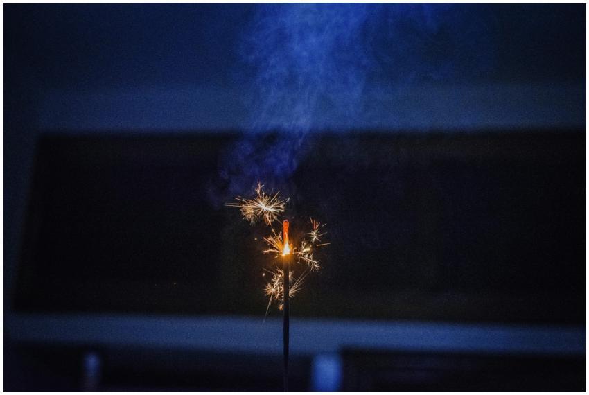 A close-up view of a sparkler igniting against a d