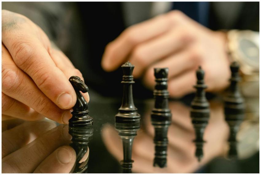 Close-up of a hand moving a chess piece on a refle