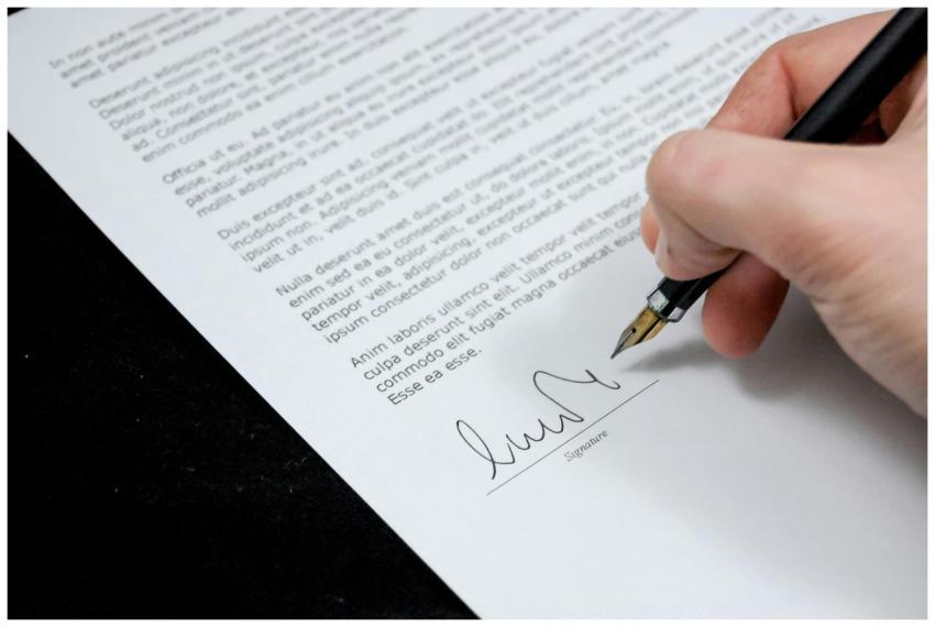Close-up of a hand signing a formal document with