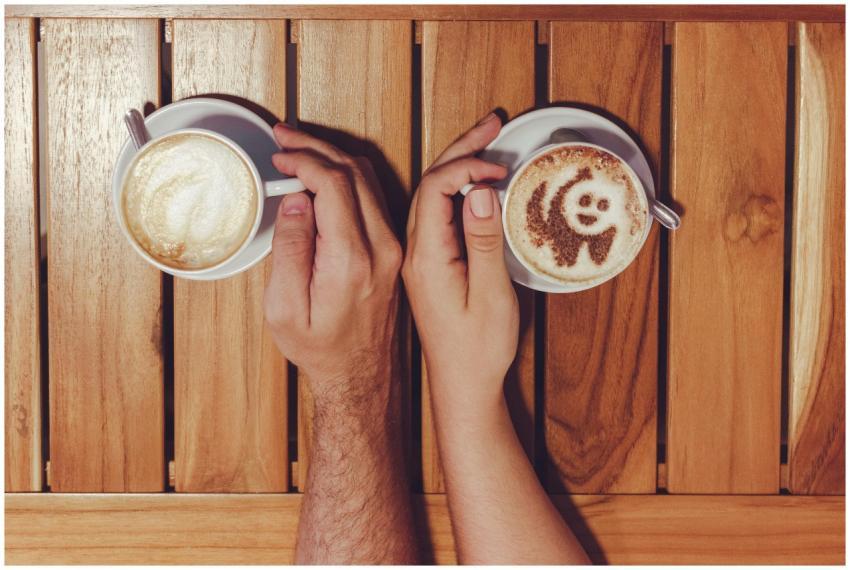 Two adults holding cups of coffee with intricate l