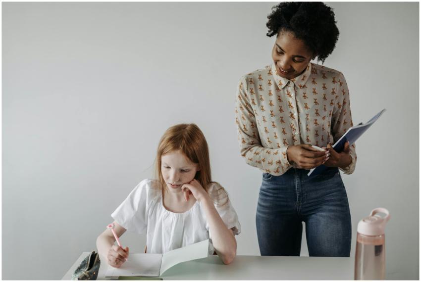 A teacher guides a student with her writing assign