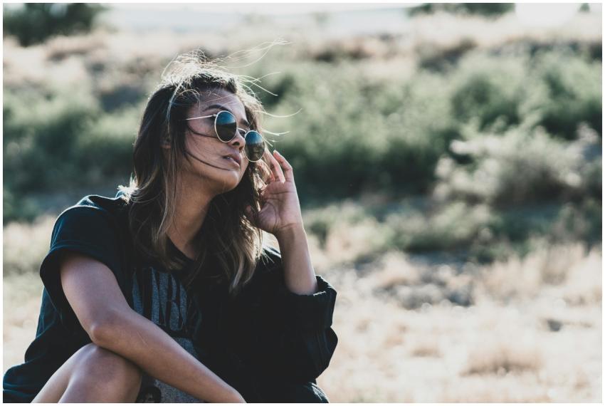 A woman in sunglasses poses stylishly in a sunny d