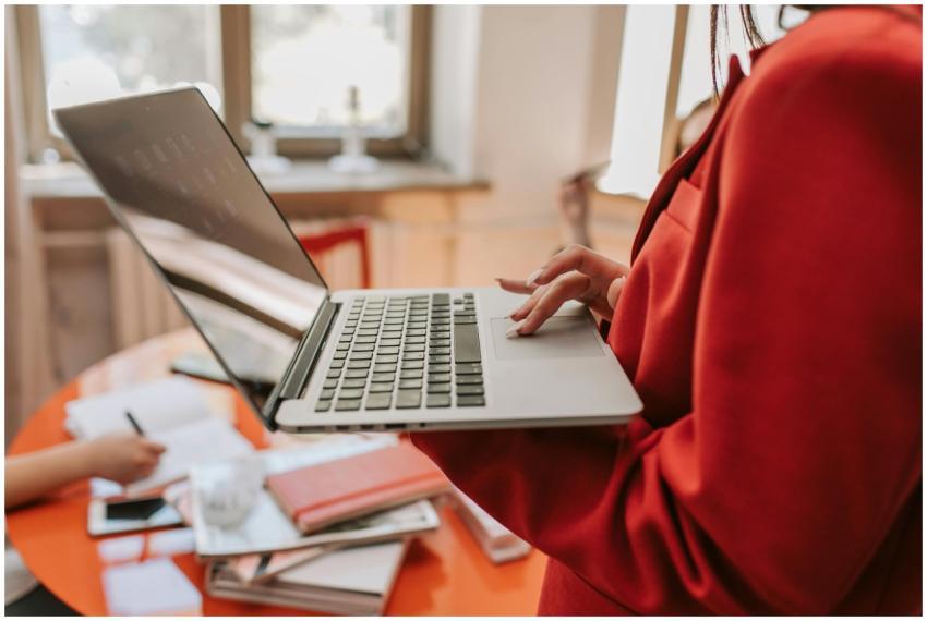 Focused businesswoman in a red blazer using a lapt