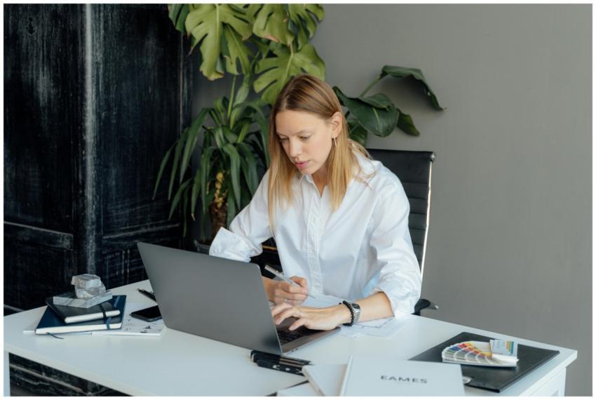 Focused woman in white shirt working on laptop at