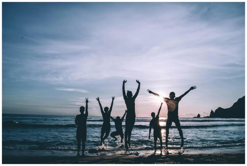 Silhouetted group of friends jumping joyfully on t