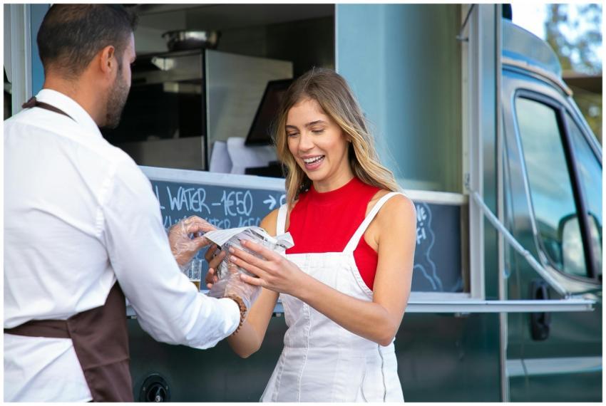 A cheerful woman receives a meal from a friendly f