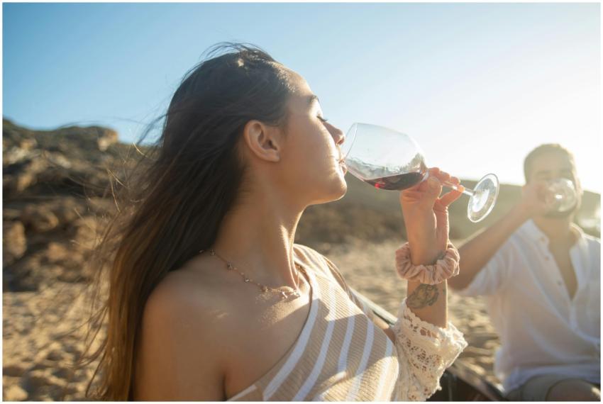 Woman savoring wine at a sunny beach in Portugal,