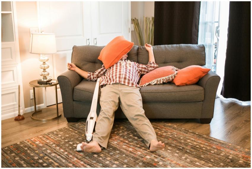 A man lies humorously on a couch, surrounded by or