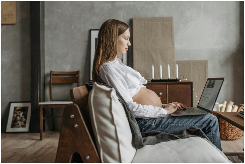 Side view of a pregnant woman using a laptop at ho