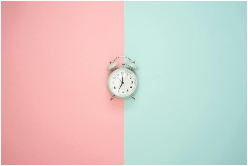 A vintage round clock on a split pastel pink and b