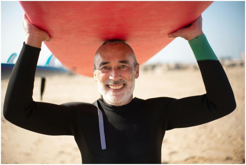 Smiling senior man holding a surfboard on a sunny