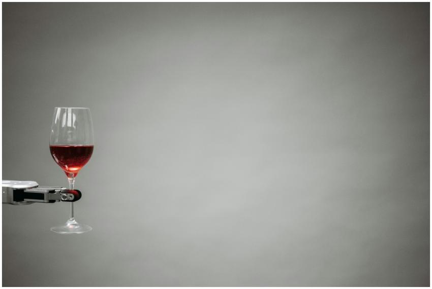 A robotic arm precisely holding a glass of red win