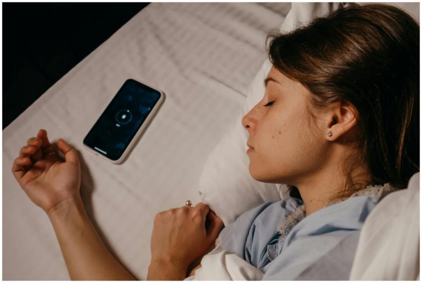 A woman sleeping peacefully in bed beside her smar