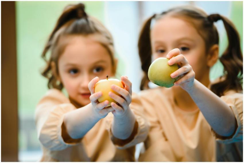 Two young girls smiling and holding yellow and gre