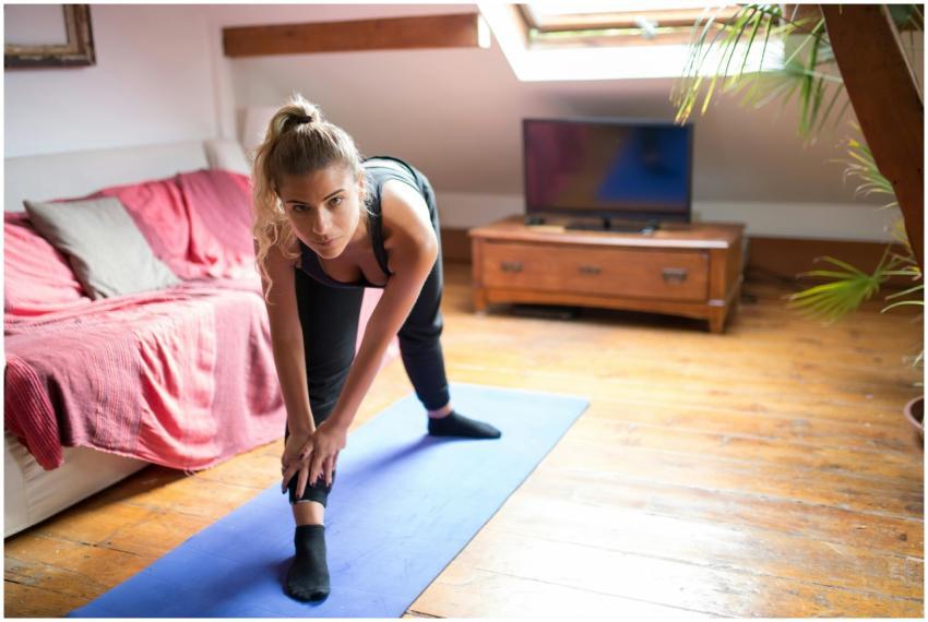 Woman exercising indoors on a yoga mat, stretching