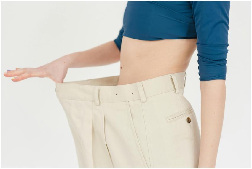 A woman demonstrates significant weight loss by we