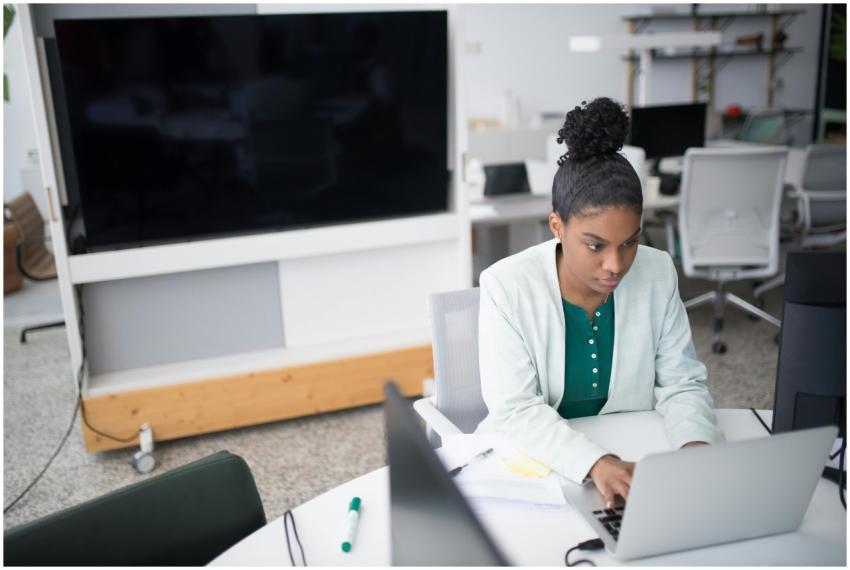 Focused woman using a laptop in a modern office se